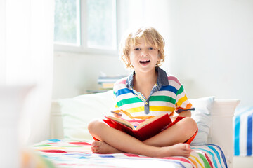 Fototapeta premium Child reading book in bed. Kids read in bedroom.