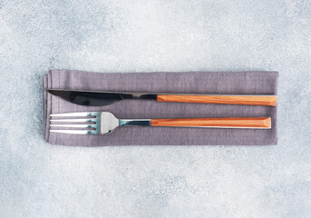 Cutlery knife and fork on a napkin, gray concrete background, copy space top view. © Elenglush