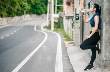 Asian fitness runner body closeup doing warm-up routine on beach before running, stretching leg muscles with standing single knee to chest stretch. Female athlete preparing legs for cardio workout.