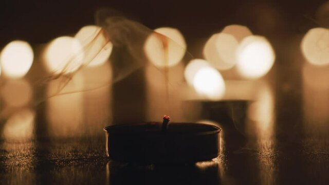 Tealight candle blows out in front of beautiful flickering backdrop.