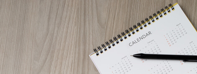calendar month schedule to make appointment meeting or manage timetable each day lay and pen on wooden background for planning work and travel concept. banner copy space.