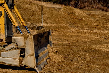 Blade and hydraulic lift cylinders of bulldozer at new construction site.