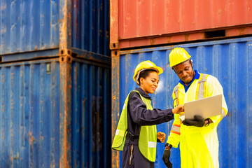 Foreman using laptop computer in the port of loading goods. Foreman talking with worker or laborer in the Industrial Container Cargo freight ship.