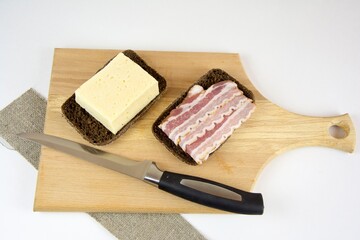 Hearty cheese and bacon sandwiches on a wooden chopping board and kitchen knife. The concept of making a quick snack