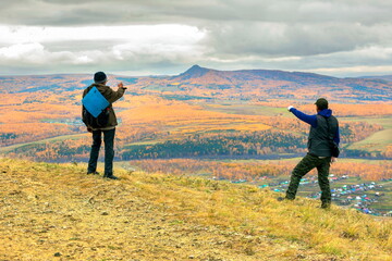 mature male tourists walk along the ridge of the big krak on an autumn day. - obrazy, fototapety, plakaty