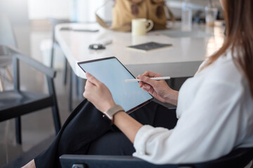 Close up of a business woman holding a tablet in hand at the office.