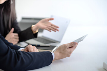 Businessman and businesswoman using touchpad and notebook in office meeting.