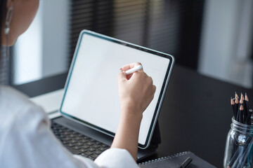 Young business woman working on a tablet with a blank screen on the office desk.