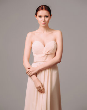 Bridesmaid's dresses. Elegant moscato dress. Beautiful pink chiffon evening gown. Studio portrait of young happy ginger woman. Transformer dress idea for an event.