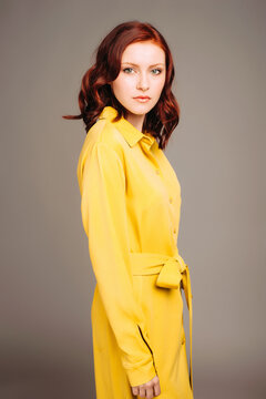 Young ginger woman in yellow shirt dress. Female bright look, lemon casual style. Fashion portrait on neutral studio background.