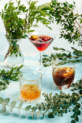 Assorted variety of different cocktails on the blue background decorated with leaves