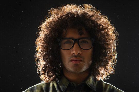 A YOUNG MAN WITH CURLY HAIR LOOKING ABOVE IN DOUBT AND THINKING	