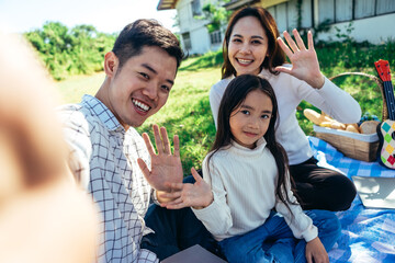 Happy Asian family having a picnic in the garden and having a happy selfie together.