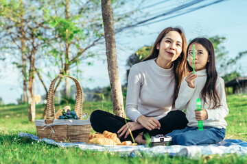 Happy asian family in the garden They are having fun playing and blowing bubbles.