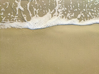 white foams on the yellow sand in sunny day