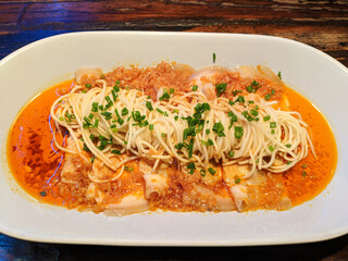 noodles on the braised pork in the red oil in white plate for eating