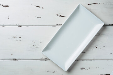Top view of a white rectangular plate on a white wooden background. Flat lay. Copy space.