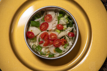Vegetable salad in metal casserole on yellow background