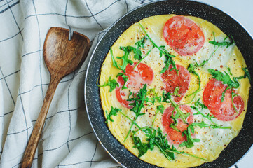 tasty italian style vegetarian breakfast - fried eggs frittata ot omelete with mozarella cheese, arugula and tomatoes