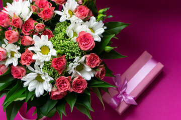 greeting card  bouquet  of pink roses and white chrysanthemums  with pink  gift box on a pink background .