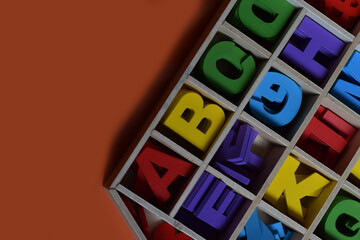 Colourfull Wooden Alphabets in A Wooden Box Organiser, isolated with Orange Background