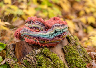 colored wool yarn skeins on an old wooden stump, handicraft concept, hand knitting, autumn time, handicrafts at home