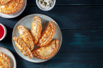 Empanadas dinner, shot from the top on a dark blue rustic wooden background with copy space