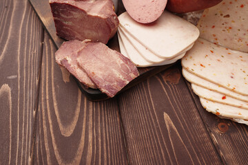 Assortment of different sausages laid out on brown wooden background