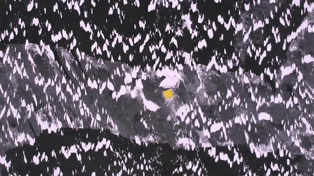 Yellow Fishing Tent Mounted On Ice Of The Lake. Icy Plane Surface With Web Of Cracks, Snow Banks And Tent Dome. Aerial Top Down View.	