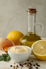 Bowl with mayonnaise and ingredients for cooking on wooden background