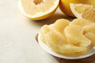Ripe pomelo and plate with pomelo slices on white textured background