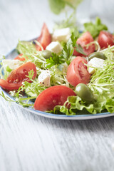 Salad with Green Olives, Tomatoes and Feta Cheese. Bright wooden background. Copy space. 