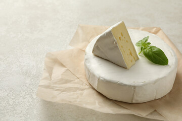Baking paper with camembert cheese on white textured background