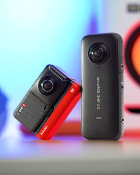 A pair of 360° action cameras by Insta360 sit on a desk with the Insta360 ONE R on the left and Insta360 ONE X2 on the right. Taken January 26, 2021 in Denver, CO.