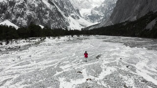 Hiker exploring old glacier river valley in Yulong Snow Mountains, aerial view