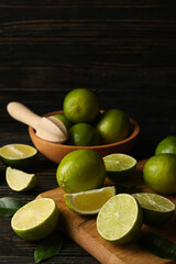 Bowl and board with lime on wooden background