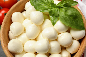 Wooden bowl with mozzarella and basil, close up