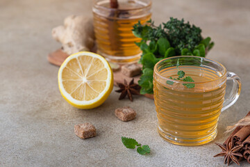 Green or herbal tea with fresh mint and thyme, cinnamon sticks, anise and ginger, light concrete background. Mint and thyme tea.
