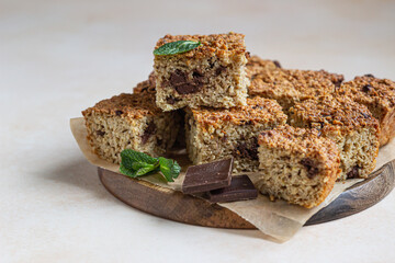 Oatmeal squares with chocolate decorated with mint, light concrete background. Diet bars. Healthy bakery for breakfast or dessert.