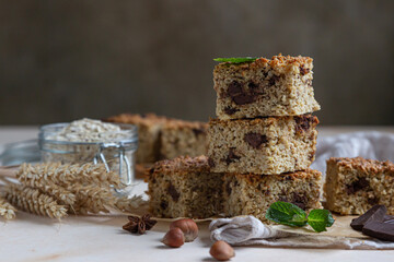 Oatmeal squares with chocolate decorated with mint, light concrete background. Diet bars. Healthy bakery for breakfast or dessert.