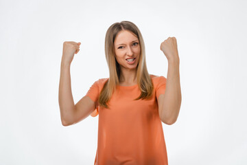 Happy blond girl clench fists and shouting yes, celebrating victory, achieve goal. Studio shot, white background