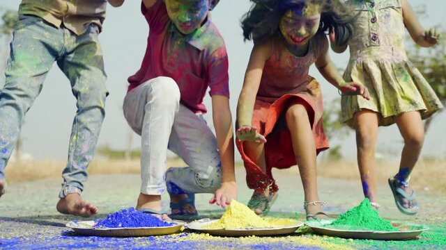 Group of kids running to taking colorful holi powder during festival celebration - Concept of kids having fun and enjoying by playing holi during festive