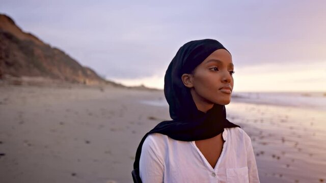 Somali-American woman walking on the beach in Malibu at sunset.