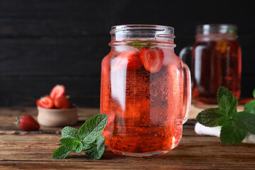 Delicious strawberry lemonade made with soda water and fresh mint on wooden table