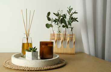Beautiful plant, candle and aromatic reed air freshener on wooden table indoors, space for text. Interior elements