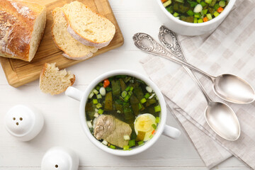 Delicious sorrel soup with meat and egg served on white wooden table, flat lay