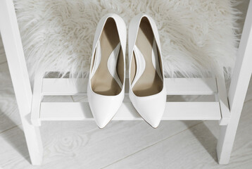 Fototapeta na wymiar Pair of white wedding high heel shoes on wooden rack indoors, above view