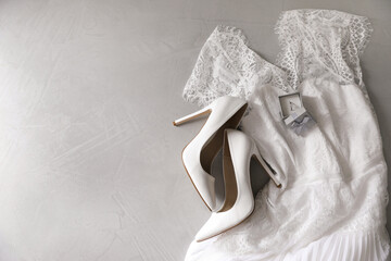 Wedding dress, white high heel shoes and ring on grey background, flat lay. Space for text