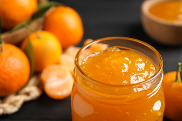 Tasty tangerine jam in glass jar on table, closeup. Space for text