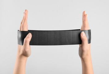 Woman with fitness elastic band on light grey background, closeup